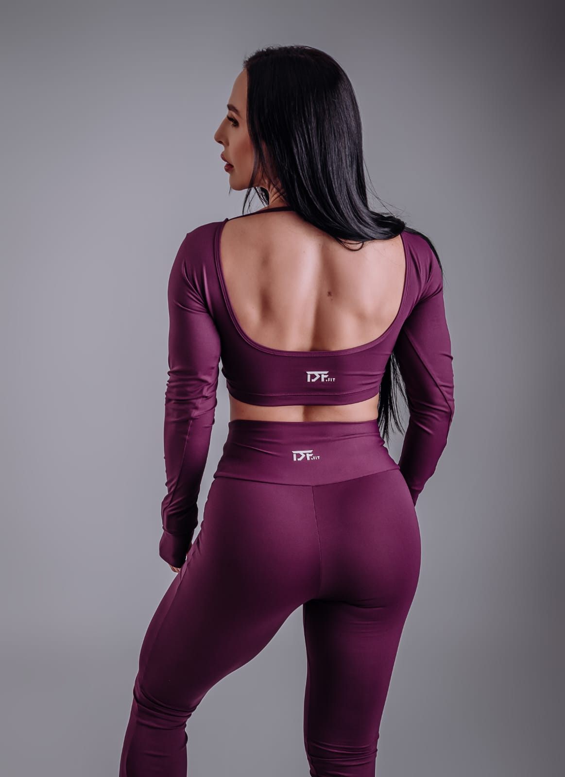 Personal trainer de costas em conjunto ameixa DF Fit, em ensaio de estúdio